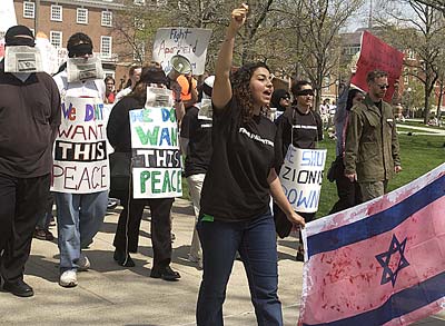 Pro-Palestinian demonstrators carrying signs and a blood-soaked Israeli flag.
