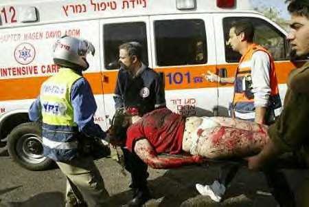 Half-naked bleeding woman terrorist victim being carried to Israeli ambulance.